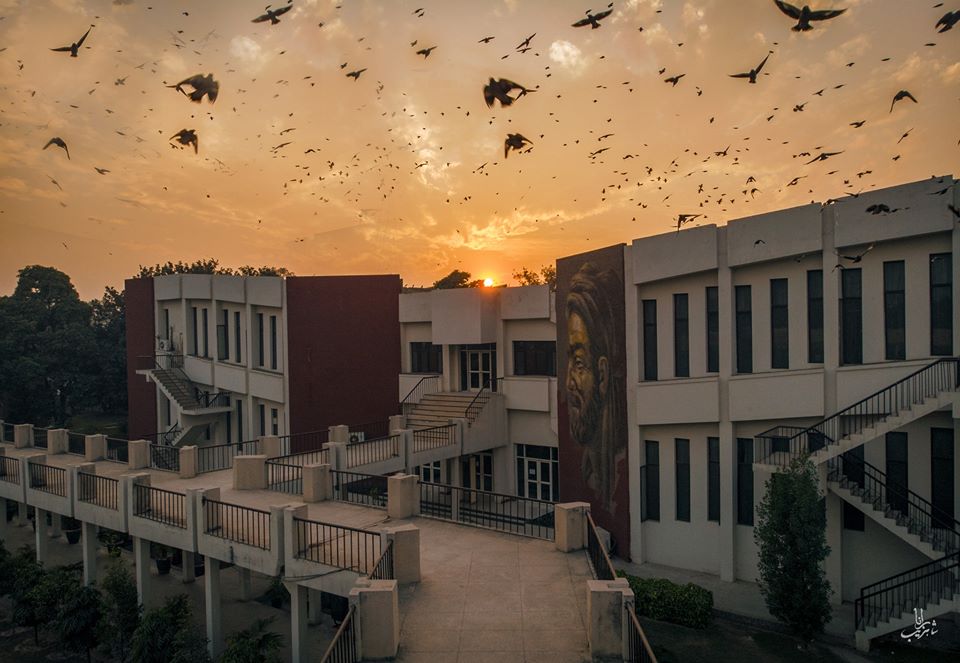 AIMC campus buildings at sunset, with a mural of Allama Iqbal